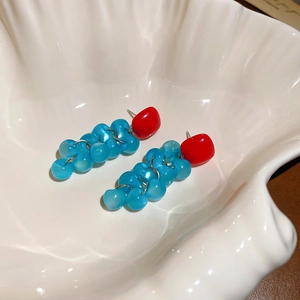 Detail of square resin earrings with red studs and light blue grape tassel clusters