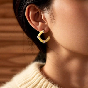 Detail view of French vintage C-shaped bamboo earrings with gold edges and rhinestones