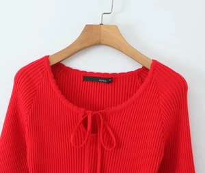 Detailed close-up of a red knit dress with lace collar and delicate tie-up neck design
