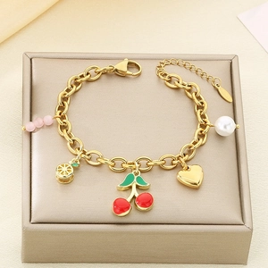Detail of gold fruit charm bracelet with cherry, lemon, and pearl charms on a display stand
