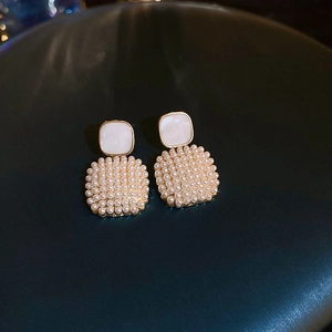 Macro detail of French vintage pearl earrings with gold frame on a textured background