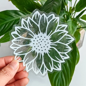 Handheld transparent suncatcher sticker with white sunflower pattern on a green background