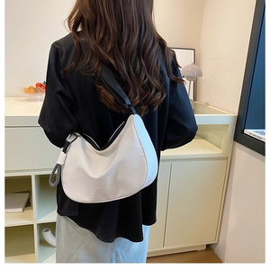 Rear view of a model wearing a stylish off-white crescent canvas crossbody bag with strap