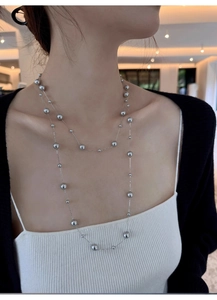 Close-up of layered silver beaded necklace with round metal pearls on an elegant model