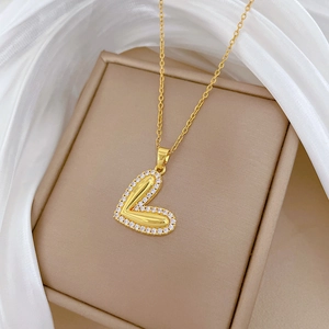 Close-up of golden heart pendant with crystal border on beige jewelry box with silk cloth