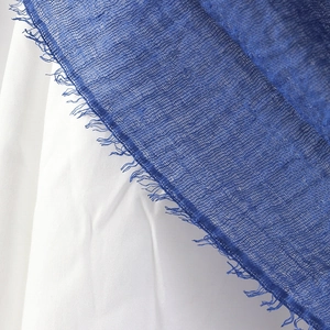 Detailed macro view of blue crinkle cotton scarf fabric with natural raw fringe edges