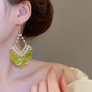 Detail of bohemian gold hollow earrings with pearls and translucent green charms