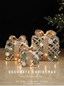 Three warm gold lighted Christmas gift boxes with jute bows and glowing LED details