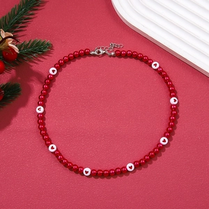 Christmas necklace with red and white pearls on a festive red textured surface