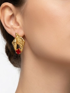 Detail of gold hammered metal earrings with red zircon and luxury fringe design