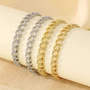 Close-up of gold and silver double-link curb chains on a minimalist beige surface