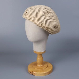Close-up of beige hollow-out knitted beret showing breathable fabric texture and detail
