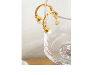 Detail of gold twisted cable C-shaped hoop earrings with elegant white pearl accents