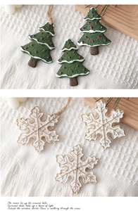 Dettaglio di decorazioni natalizie in resina a forma di albero e fiocco di neve su maglia