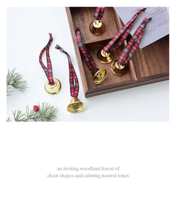 Golden Christmas bell ornaments with red and green plaid ribbon on a rustic pine background