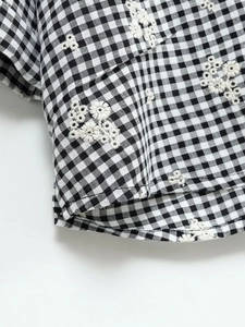 Vue détaillée du tissu vichy noir et blanc avec de délicates broderies florales blanches