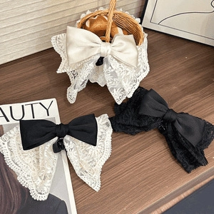 Elegant lace bow hair claw clips in cream and black displayed on a wooden surface