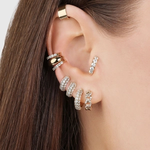 Detail of 18K gold hoop earrings set with micro-pave zircons worn on model's ear