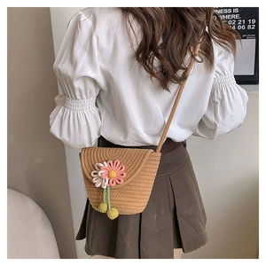 Straw bucket bag with pink flower detail shown on model in a casual summer outfit