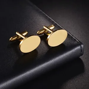 Polished gold titanium steel oval cufflinks for men on a black leather surface