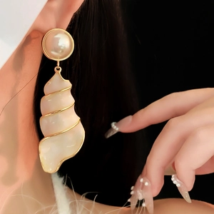 Close-up of vintage gold sea shell earrings with pearl studs on a female model