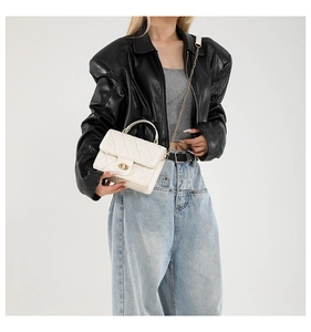 Close-up of white quilted leather texture with metallic twist lock and chain strap