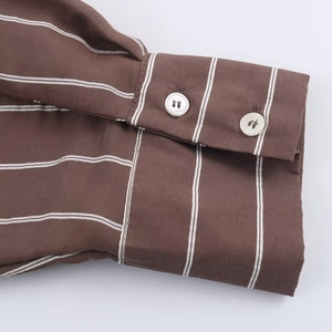 Macro shot of double-buttoned cuffs on a dark brown striped cotton shirt for women