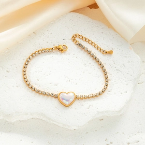 Close-up of golden tennis bracelet with heart pearl pendant and adjustable lobster clasp