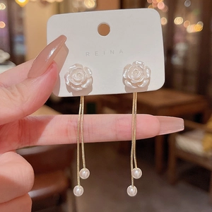 Detail of rose stud earrings featuring long gold tassel chains and elegant white pearls