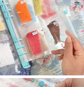 Close-up of diamond painting storage book with clear pockets and colored bead bags