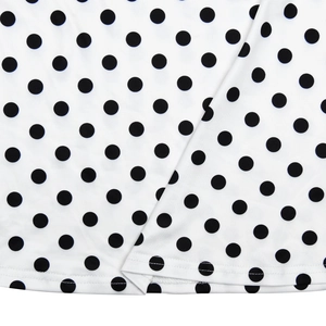 Détail macro du tissu blanc à pois noirs montrant la couture de l'ourlet et la texture