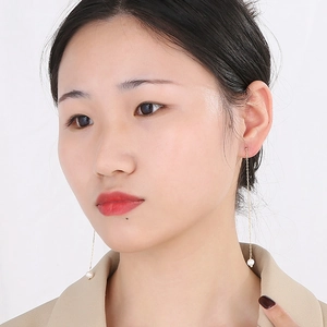 Vue détaillée des boucles d'oreilles perles dorées montrant le design long pendant