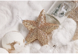 Close-up of glittery gold Christmas star tree topper with reindeer themed ornaments