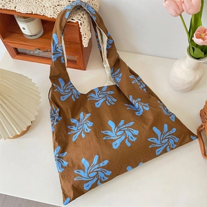 Detail of artistic floral canvas tote bag with brown fabric and blue flower patterns