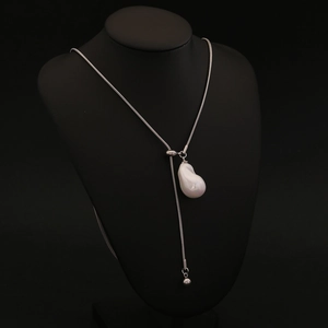 Elegant long necklace featuring a baroque pearl pendant on a silver snake chain on black bust