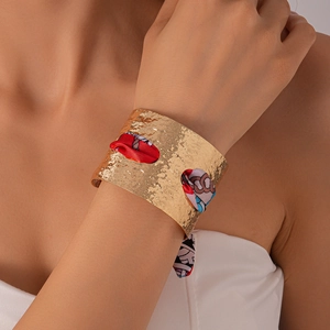 Dettaglio del bracciale rigido dorato martellato con intreccio di seta rossa e blu