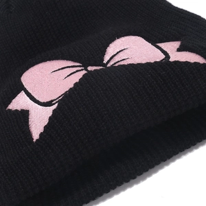 Black knit beanie with pink satin bow embroidery in a detailed 45-degree angle view