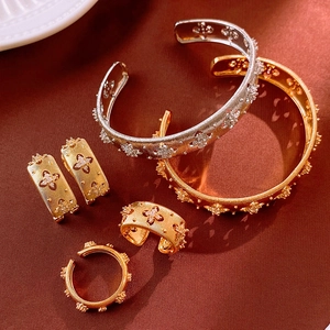 Detail of Italian style brushed metal floral jewelry set with hollow flower patterns
