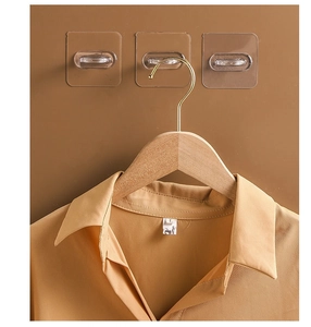 Detail of wooden clothes hanger with gold metal hook and transparent adhesive wall hooks