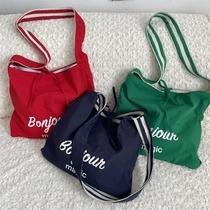 Détail de sacs cabas colorés en toile avec bandoulières rayées et texte Bonjour magic