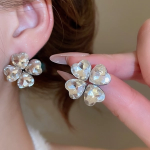 Close-up of sparkling four-leaf clover stud earrings with silver metal and clear crystals