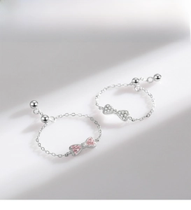 Detail of adjustable 925 silver bow rings with pink and white zircon micro-inlay