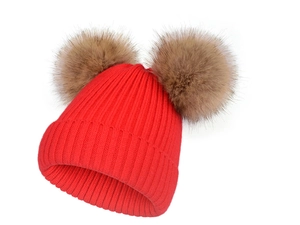 Gros plan sur un bonnet en tricot rouge avec deux pompons marrons et une texture côtelée