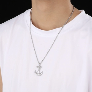 Detailed view of a silver anchor pendant necklace for men worn on a male model