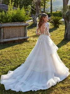 Détail d'une robe de mariée dos nu en dentelle avec boutons délicats et manches longues