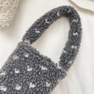Detail of plush grey heart cup sleeve with thick handle on white textured fabric