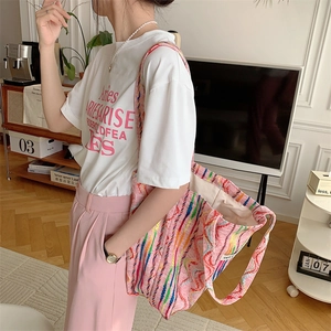 Détail du sac cabas en toile à rayures arc-en-ciel colorées porté à l'épaule d'une femme