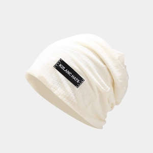 Detailed macro view of the cream white knitted beanie featuring a black KIZLANC HATS woven label