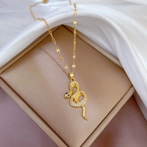 Détail macro du pendentif serpent doré avec zircons blancs sur fond en satin blanc