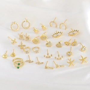 Collection of golden stud earrings with white zircon in star, crown, and shell shapes